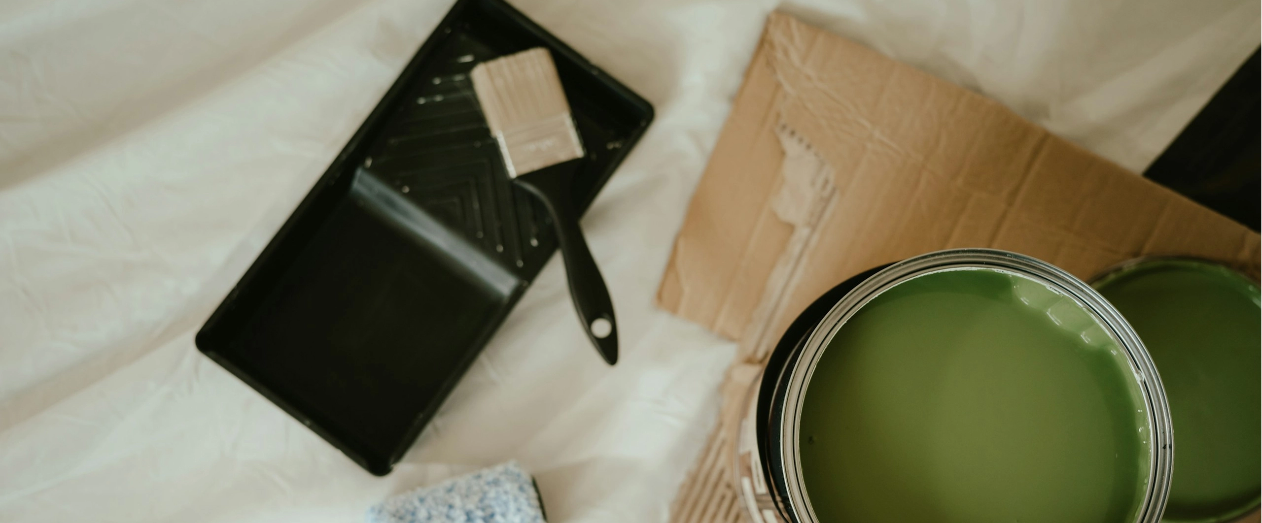 Open green paint can with brush resting on tray, ready for home improvement project.